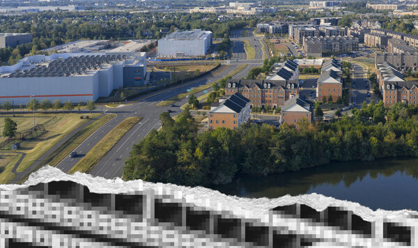 Aerial view of a data center campus alongside suburban housing and a wooded pond