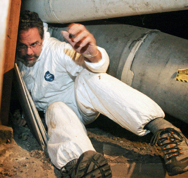 Peter Yost in a Tyvek suit, crammed in a crawlspace