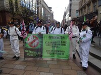 Protesters dressed as the ghostbusters hold a sign saying “greenwash busters."