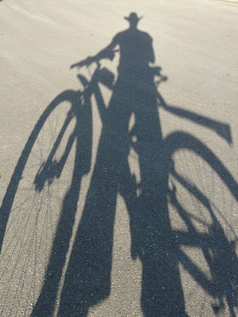 Picture of the shadow of a cowboy with a bicycle, reflected in sand.