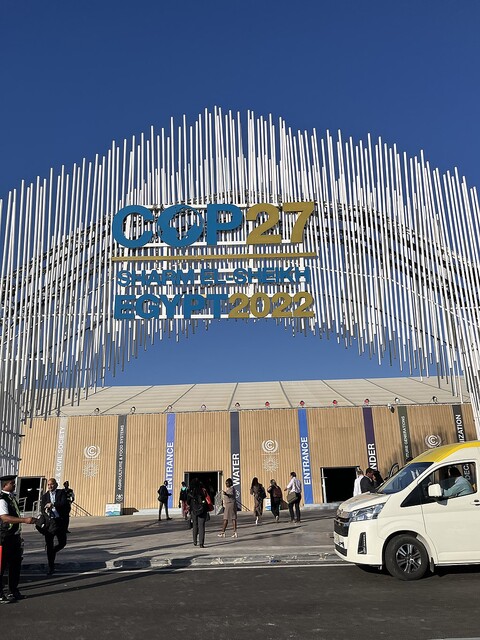 A large arch made of small metallic pipes with the words "COP27  Egypt 2022" marking the entrance to the COP27 conference.