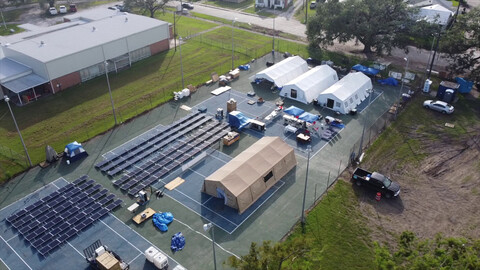 Footprint Project disaster support with solar panels and tents set up on tennis courts.