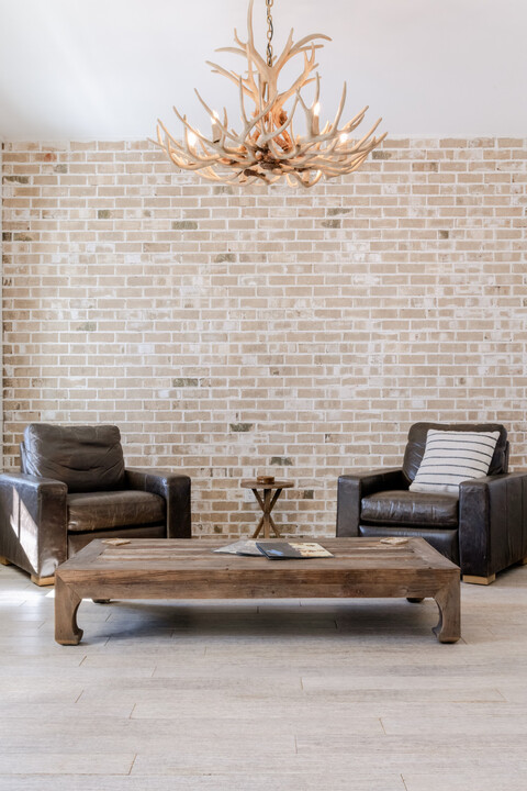 HempWood flooring in a living area with brick backwall, two dark brown chairs, and a gold chandelier.