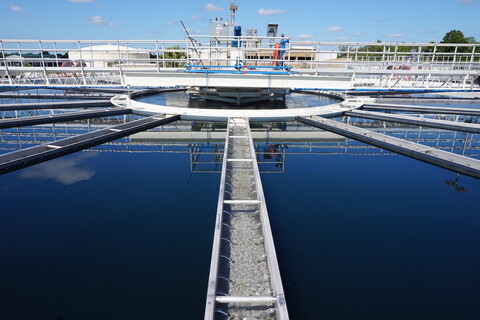 part of a water treatment plant, a large round tank full of dark blue water. 