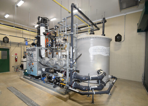 A large Innovatreat water treatment system with tank, filters, and controls in a cement room
